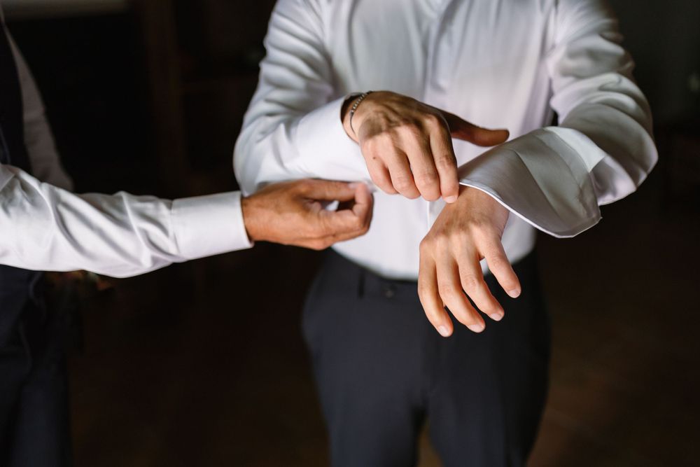Close up view of someone adjusting the cuff of a crisp white dress shirt while getting ready.