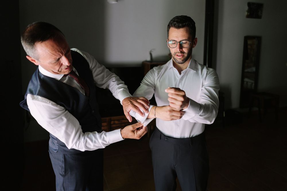 Two people in formal attire examine a men's watch in a dimly lit room.