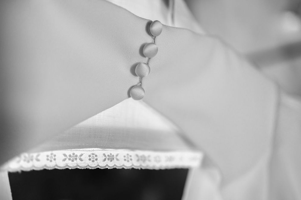 Black and white detail shot of delicate ivory lace trim on wedding dress fabric.