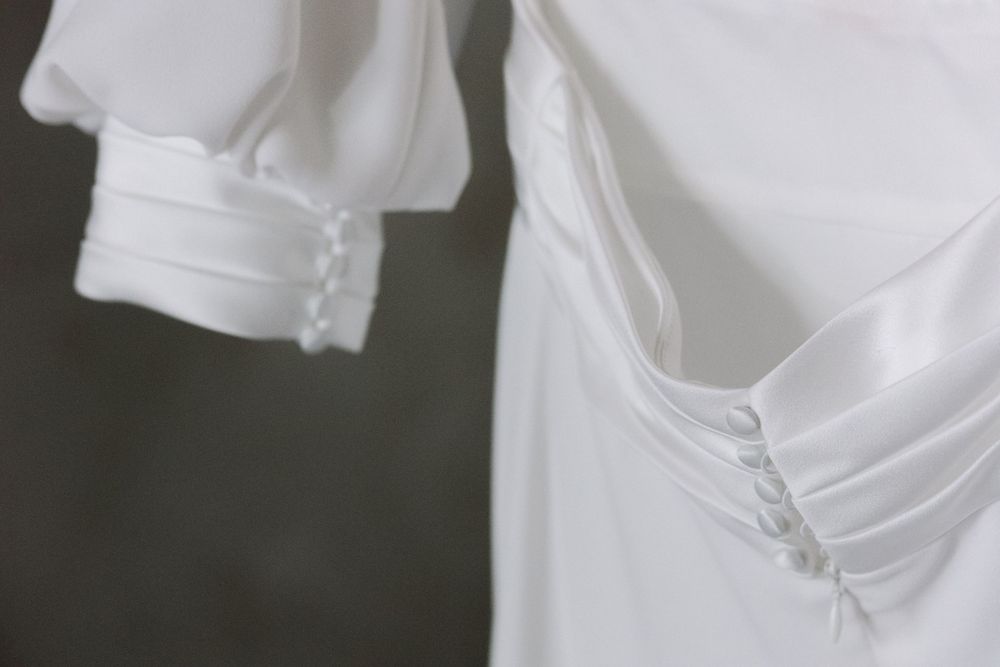 Close-up detail of white fabric with delicate button closures and gathered material.