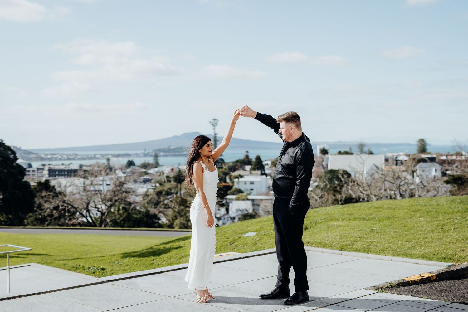 Four artistic engagement photos show a couple posing between white stone columns at a historic landmark building.