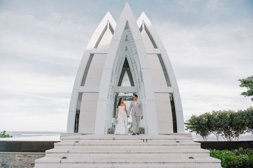 A modern white church building with geometric architecture and multiple pointed spires against a cloudy sky.