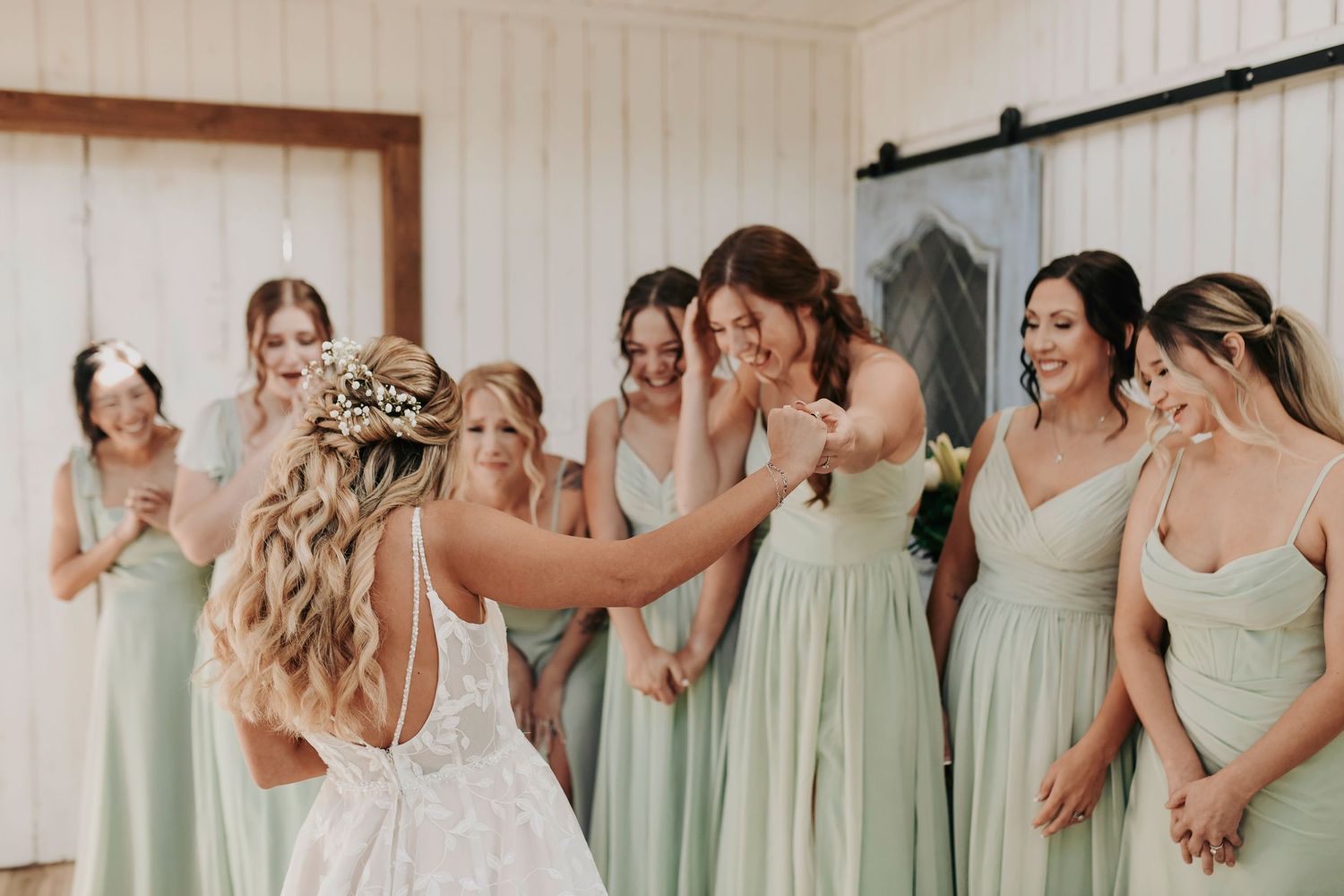 Bride laughing as bridesmaids cheer during first look