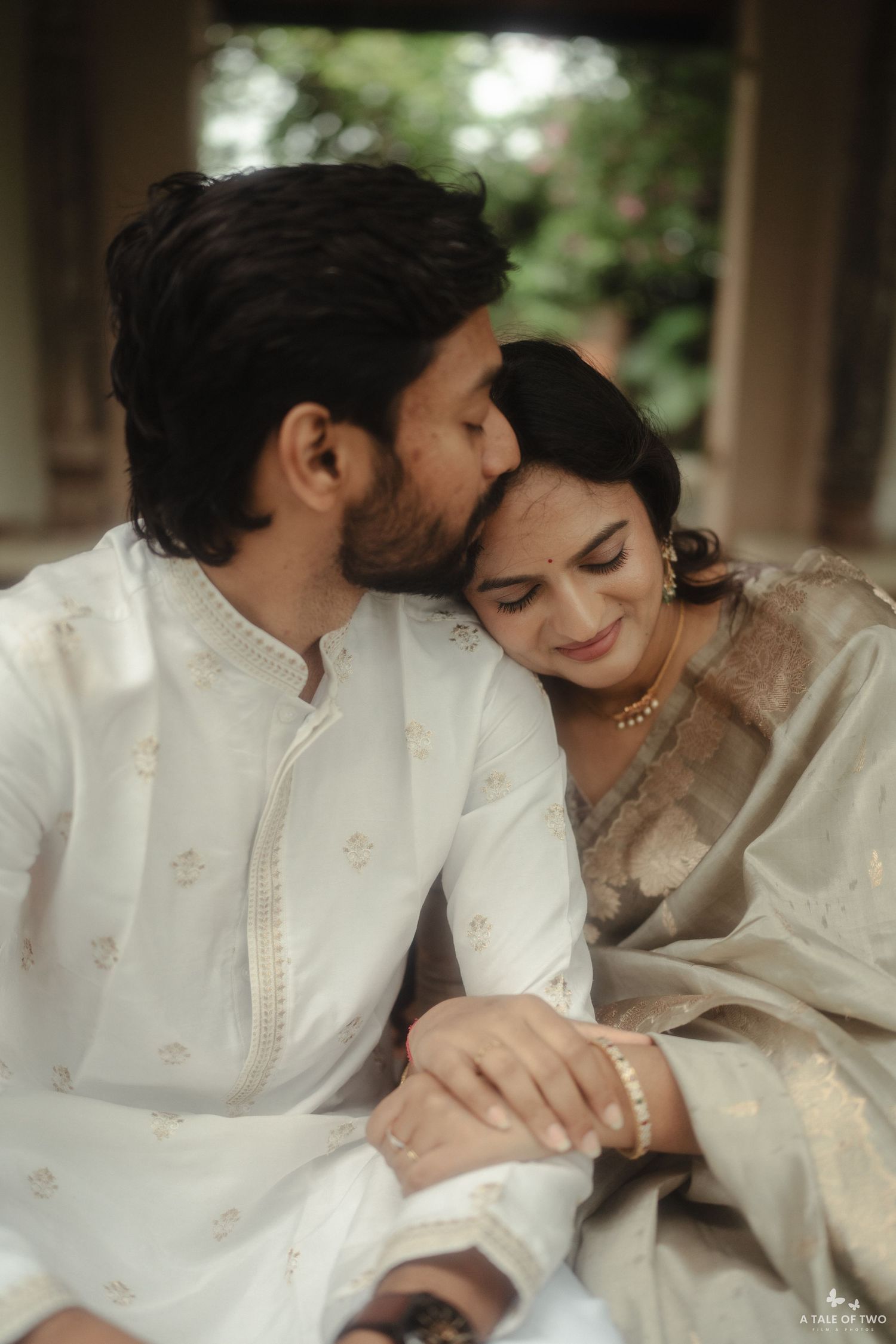 An intimate photoshoot featuring a couple in traditional white attire sharing sweet moments together.