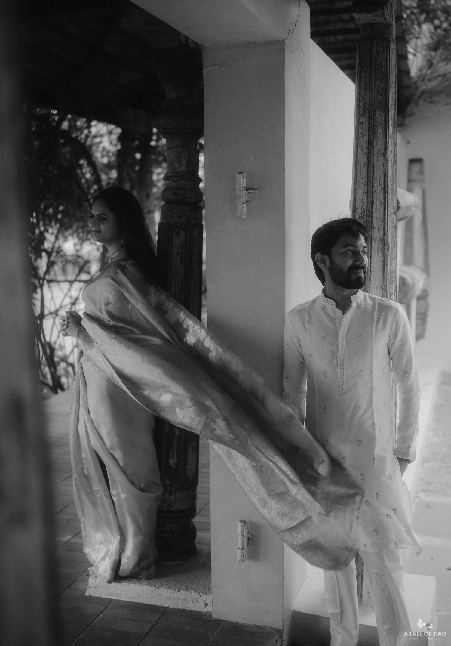 Artistic black and white double exposure photograph showing a figure in white clothing with motion blur against a doorway.