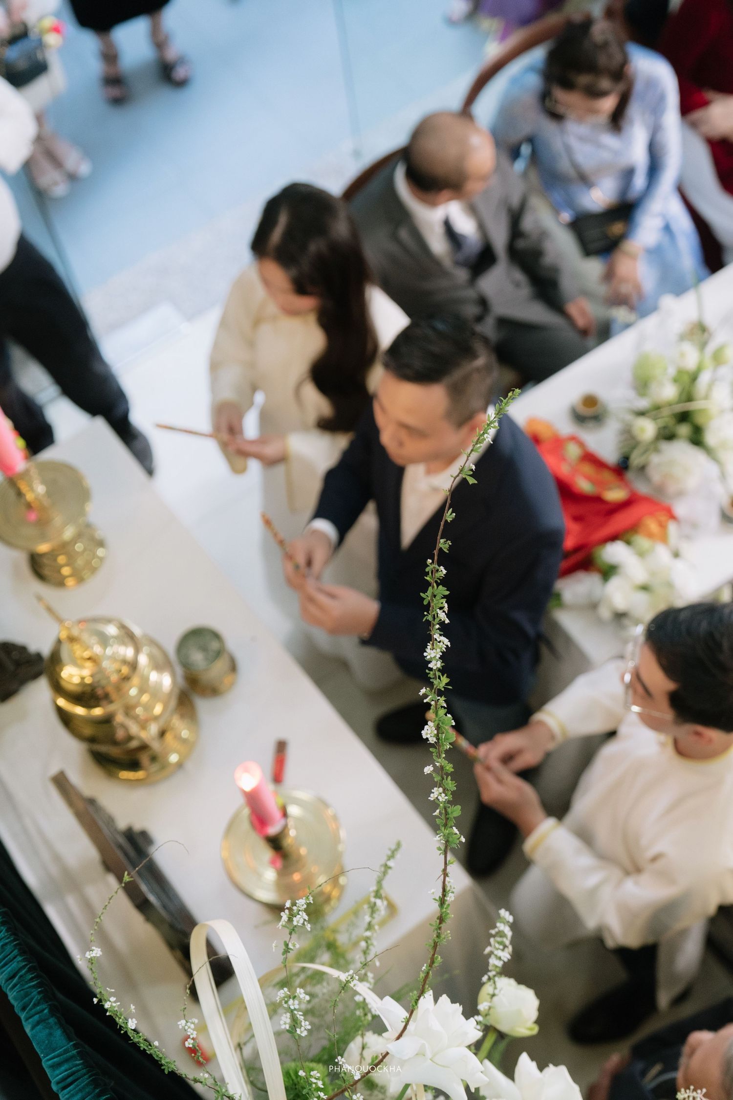 Overhead view of guests lighting incense sticks at a traditional Vietnamese ceremonial altar table.