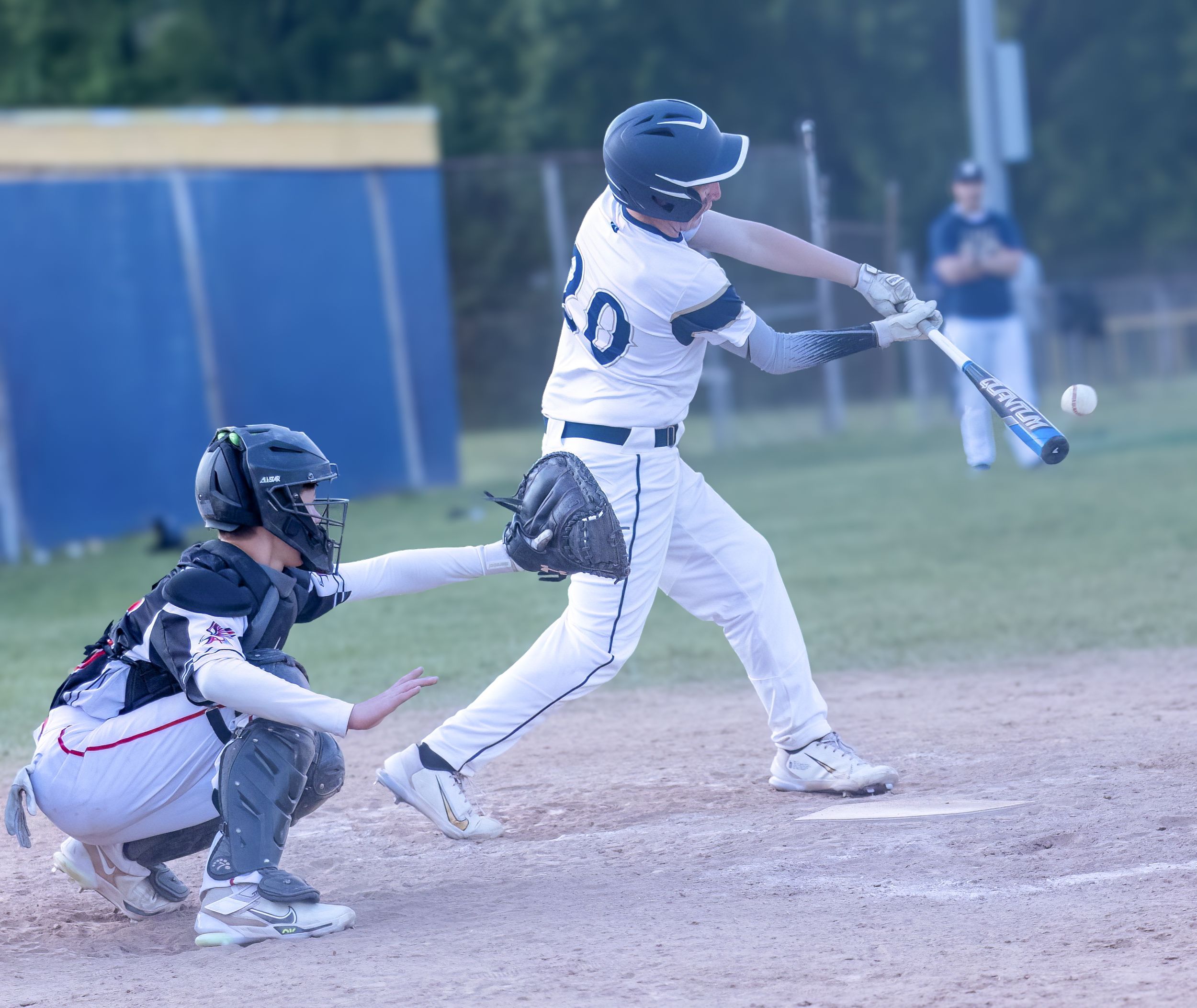 Baseball batter making contact with the ball during a game while the catcher crouches behind home plate.
Baseball DuPont middle school kanaw