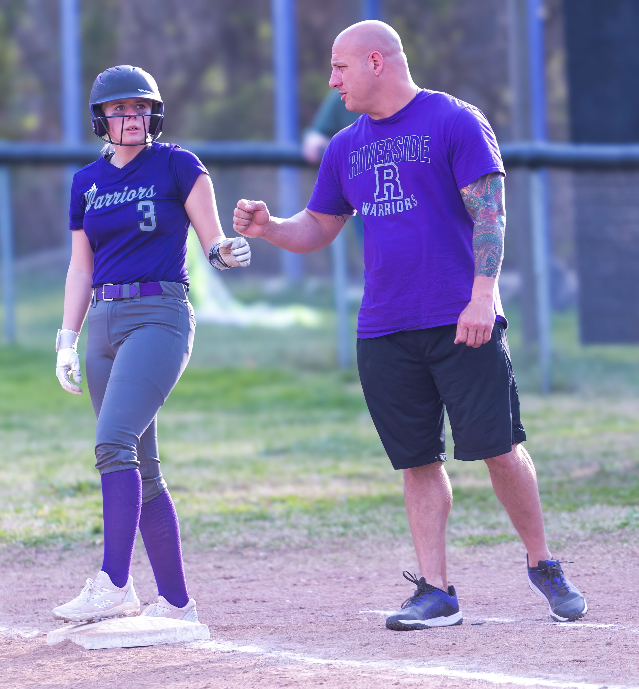Coach in purple team shirt giving instruction to a softball player on the field.
Softball riverside high school kanawha county