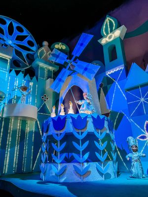 A vibrant blue and teal illuminated It's a Small World attraction with geometric shapes and floral patterns in Disneyland.