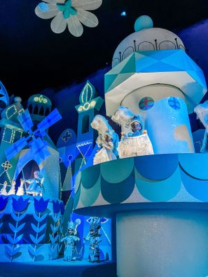 Inside It's a Small World ride at Disney showing blue-lit scenes with white floral decorations and animated figures.