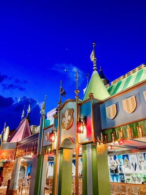 Colorful whimsical architecture of the Seuss Landing attraction at Universal Studios illuminated against a deep blue sky.
