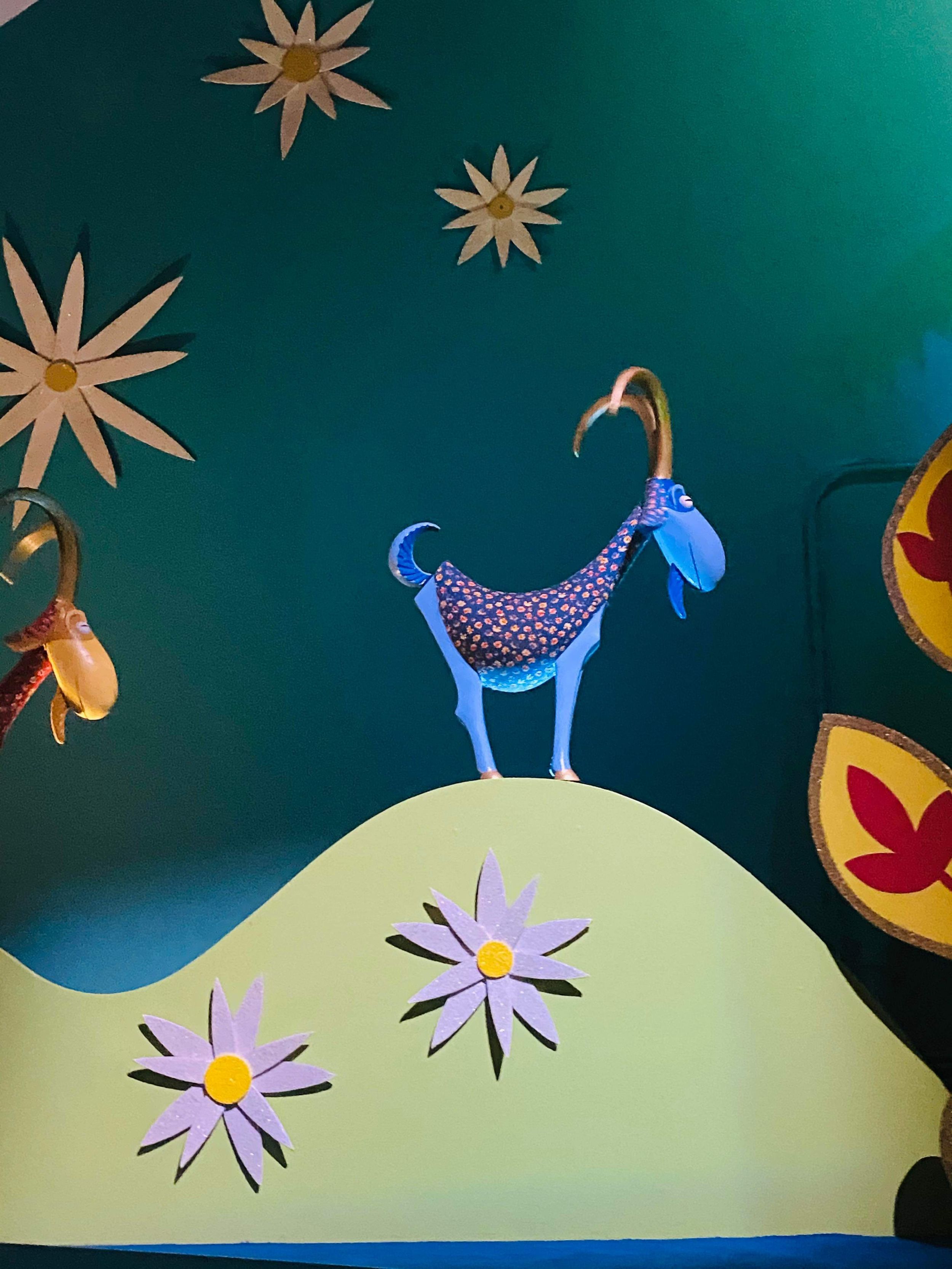Decorative wall art featuring stylized blue birds perched on yellow hills against a teal background with golden stars.