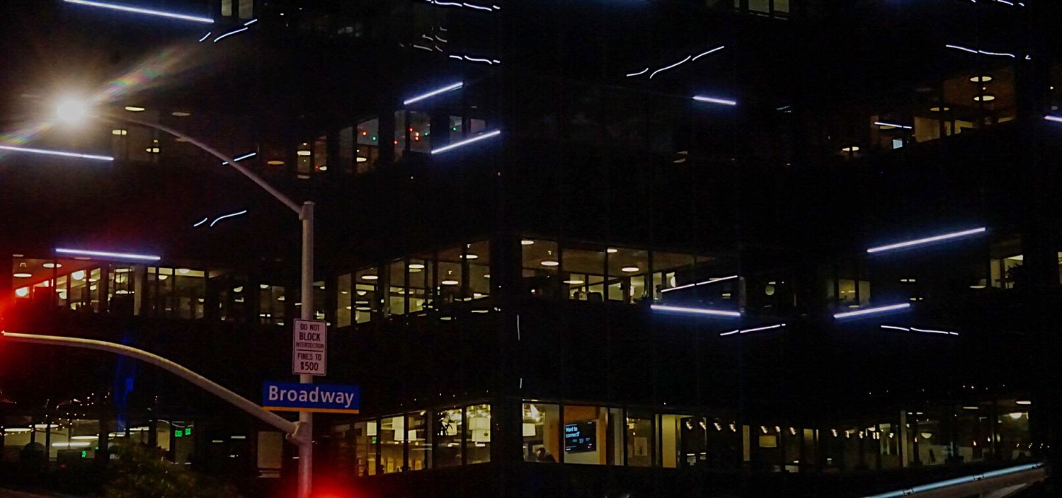 City skyline at night with glowing neon lights and illuminated buildings creating an urban atmosphere.