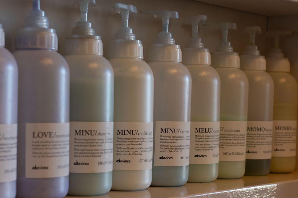 Row of white product bottles lined up on wooden shelf displaying various beauty or wellness items.
