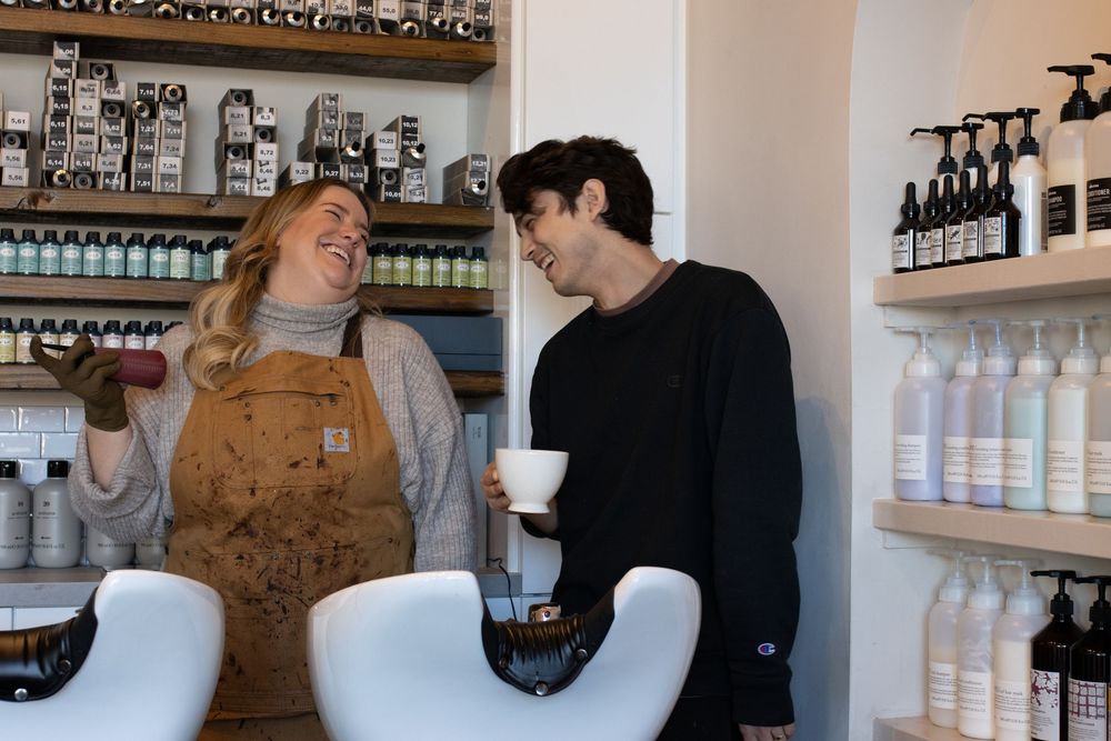 Staff members working together in retail shop with product displays on wall shelving.