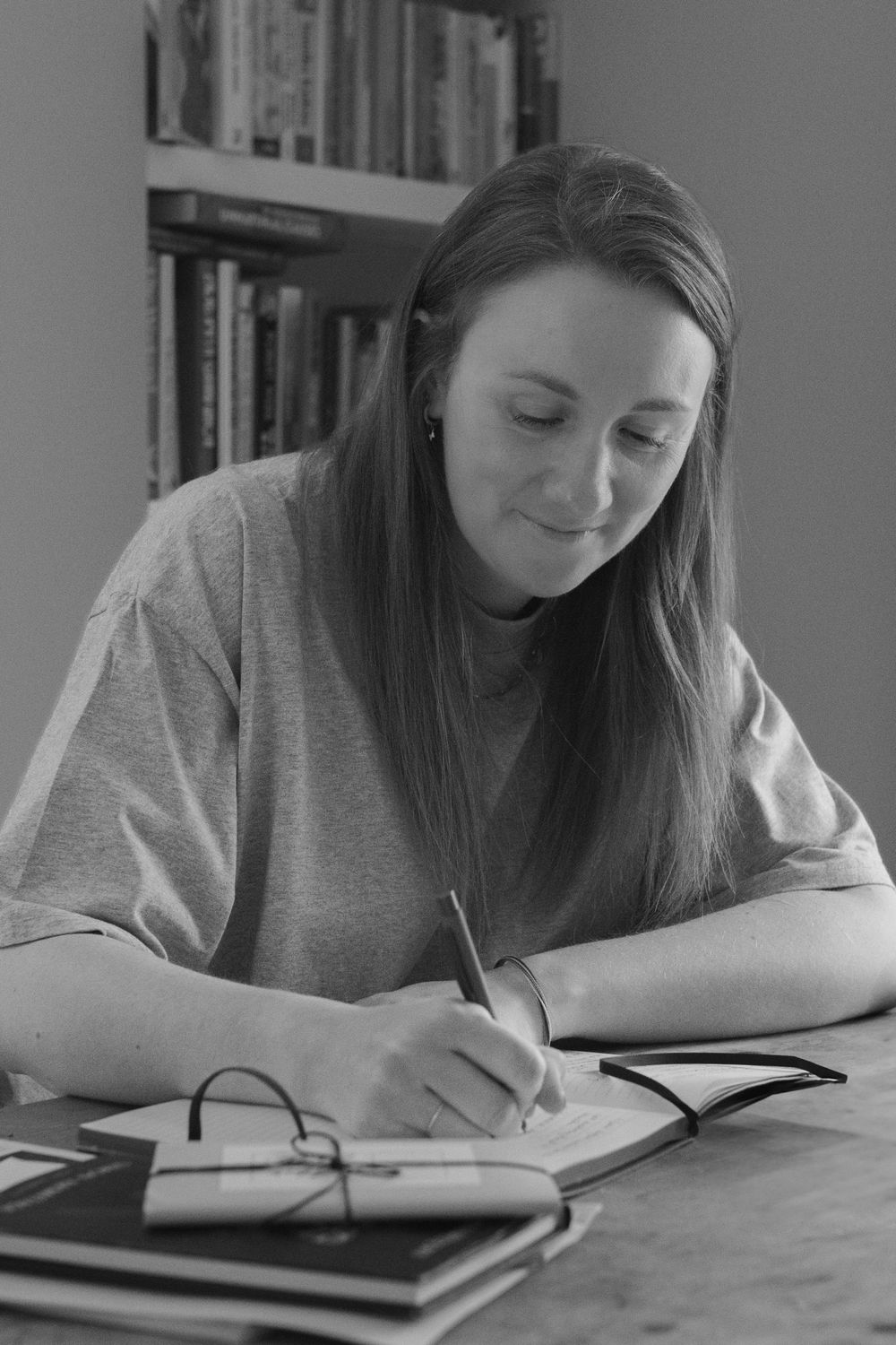 Person writing in journal at desk in black and white composition.