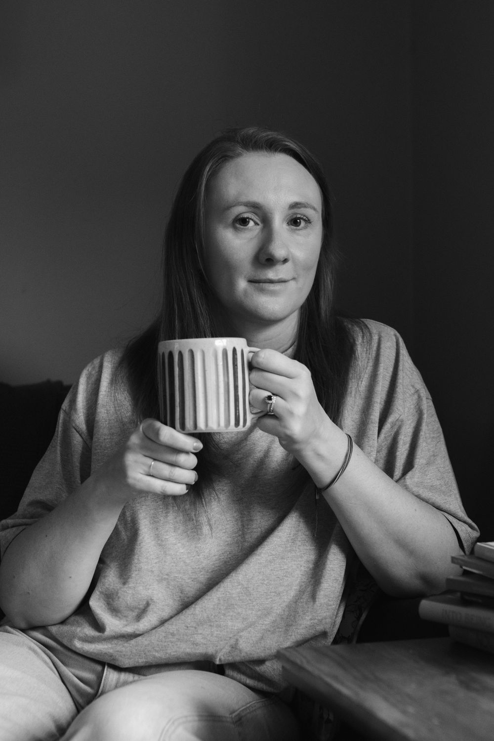 Person holding white coffee mug while relaxing in black and white composition.