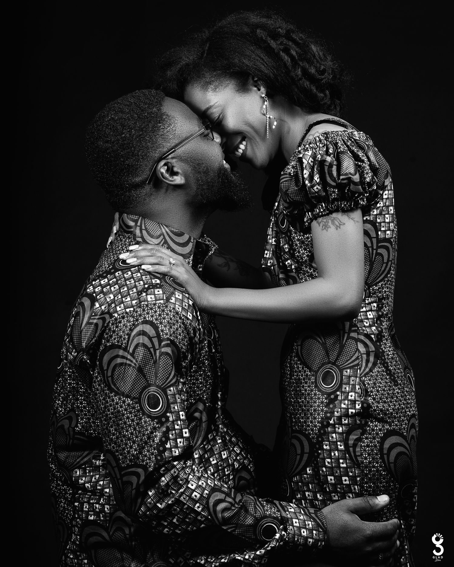 Intimate black and white portrait of a couple in matching patterned outfits sharing a tender romantic moment together.