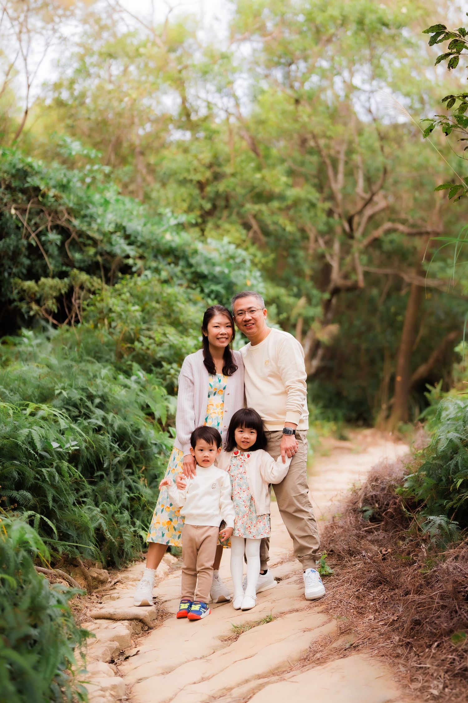 A family walking together on a nature trail surrounded by lush green foliage at Battleship Rock Hike Junjianyan in Beitou Taipei Taiwan
