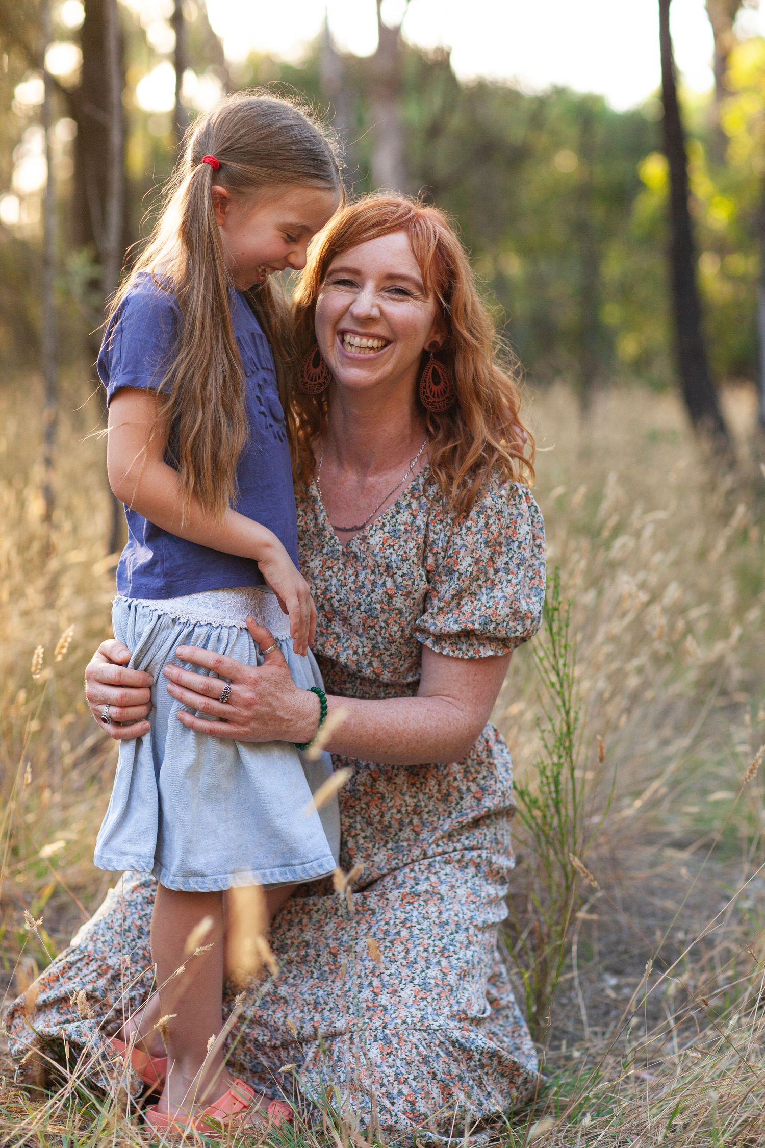 A sweet moment shared between a parent and child embracing in a sunlit field of tall grass at golden hour.
