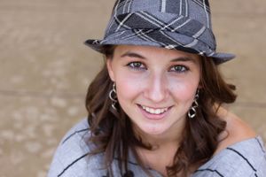 Portrait wearing patterned grey fedora hat and earrings.