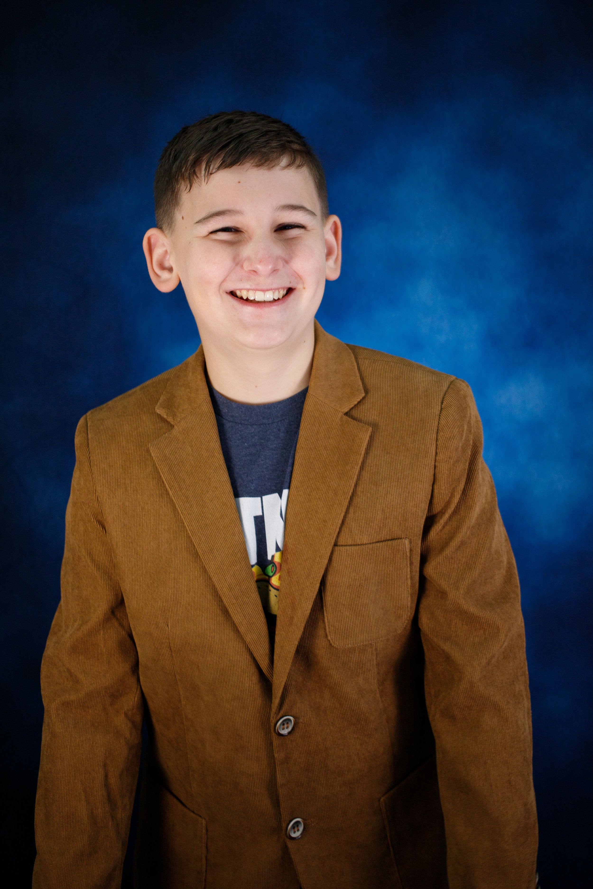 Portrait series showing warm brown blazer against deep blue studio background.