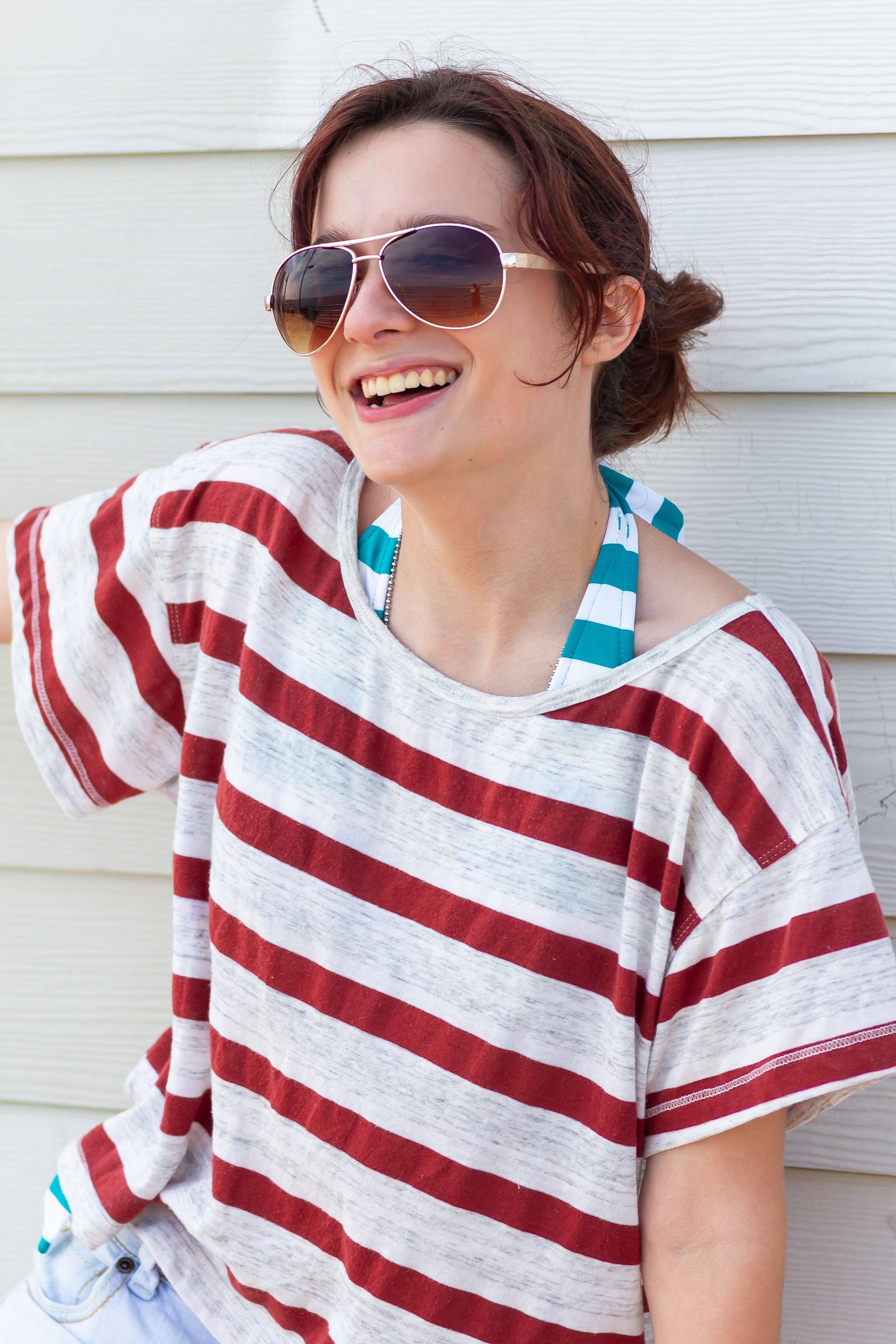 A cheerful moment captured wearing red and white striped shirt with aviator sunglasses and turquoise accents.