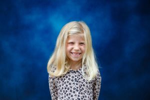 School portrait of a young student wearing a leopard print top against a blue background.