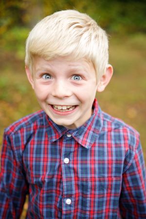 School portrait of a child in a red and blue plaid button-down shirt with a bright expression.