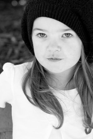 Black and white portrait showing someone in a knit beanie and white shirt.