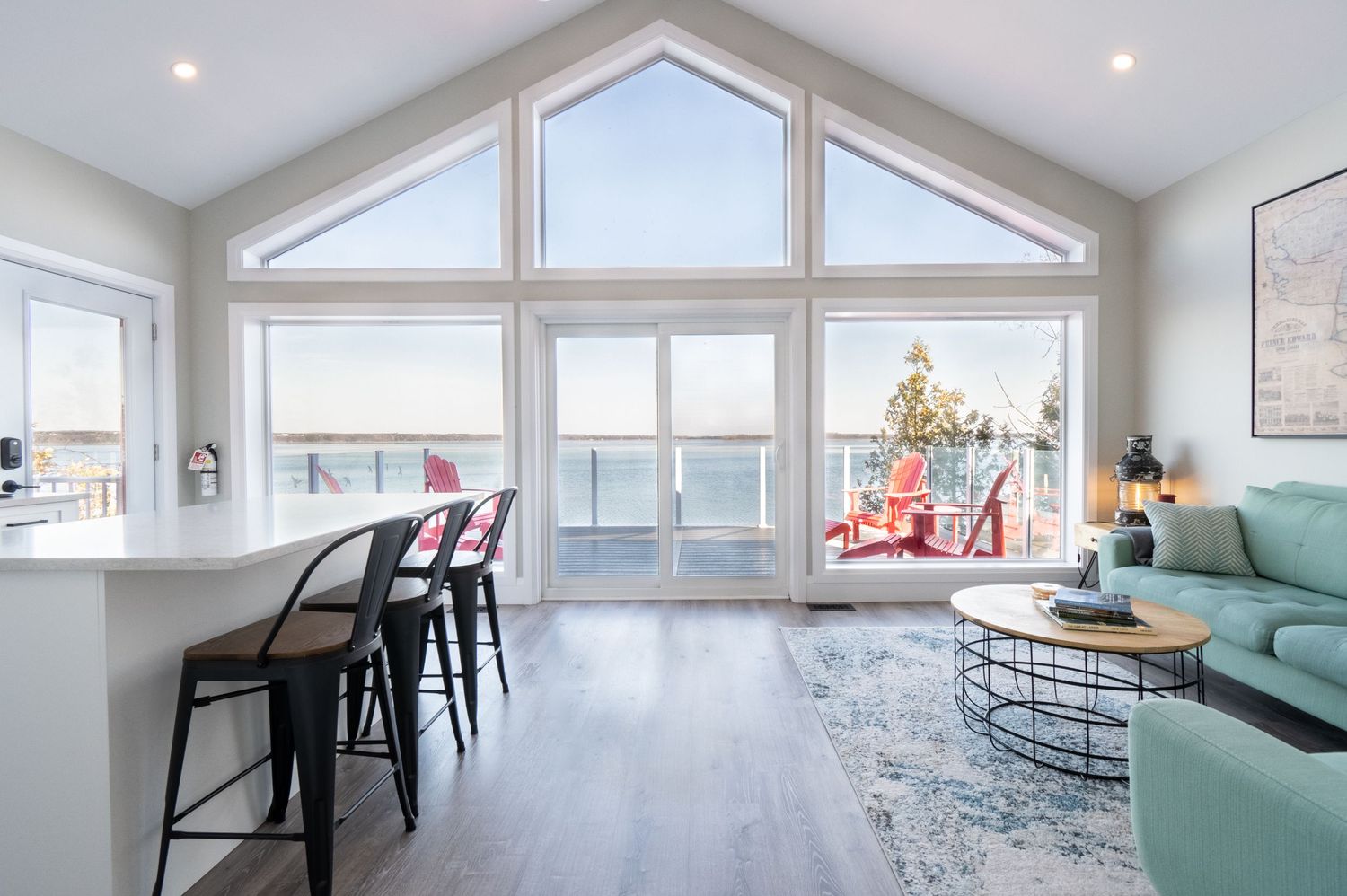 Modern living room with vaulted ceiling, large windows, and Christmas tree overlooking a scenic view.