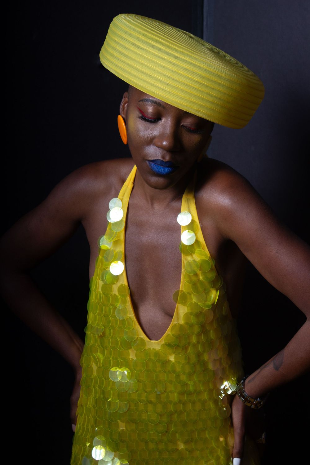 Artistic fashion portrait with yellow circular hat and matching sequined dress.
