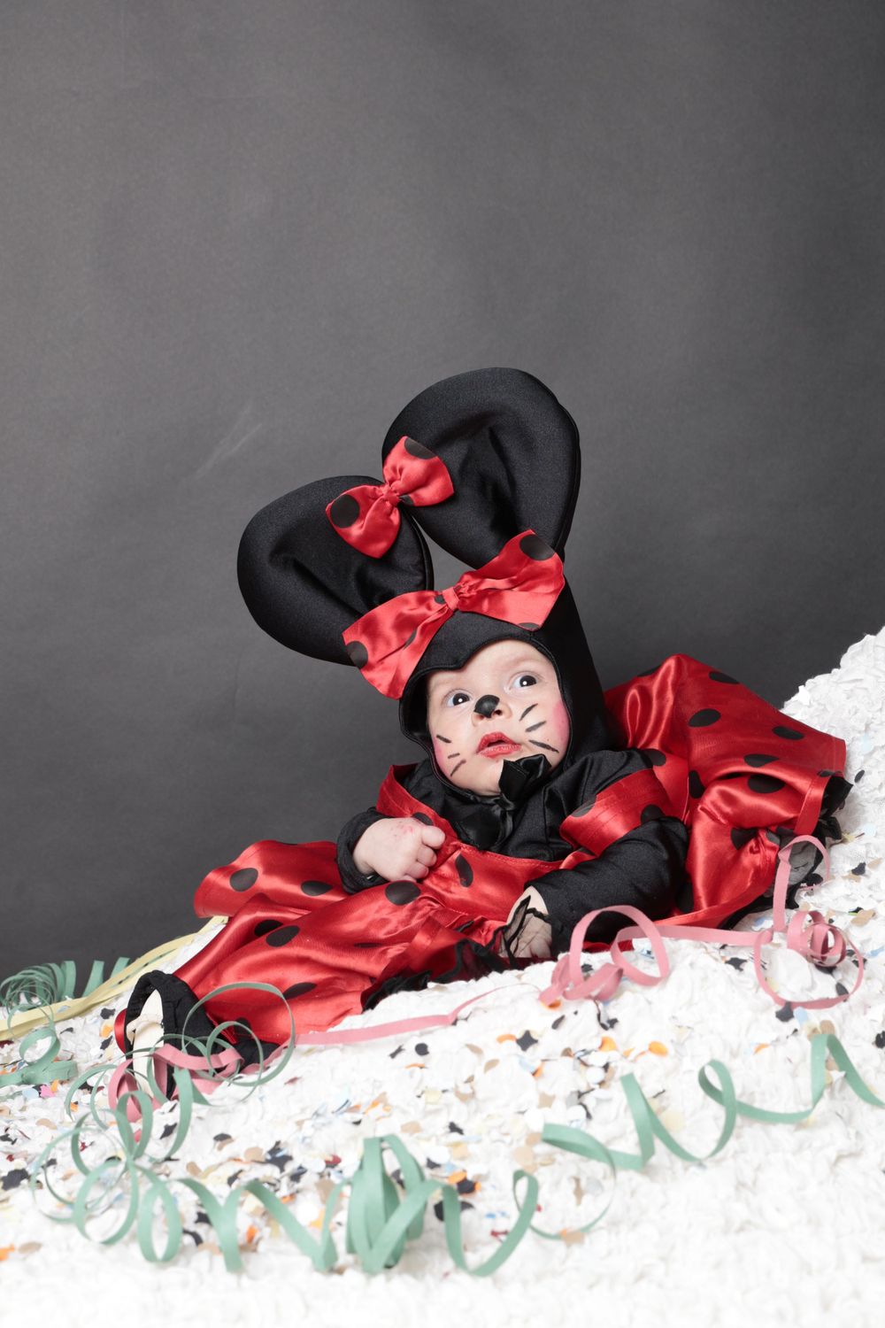 An adorable Minnie Mouse costume on a small figure surrounded by pale green and white decorations.