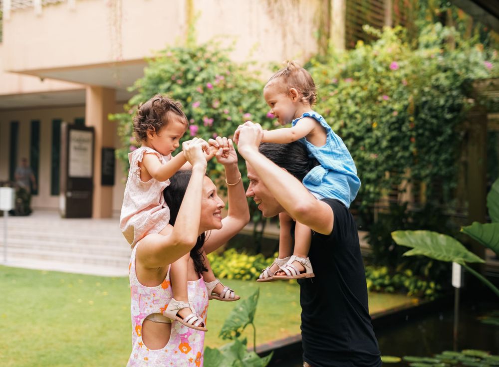 A joyful moment captured as someone lifts a child high in the air outdoors.