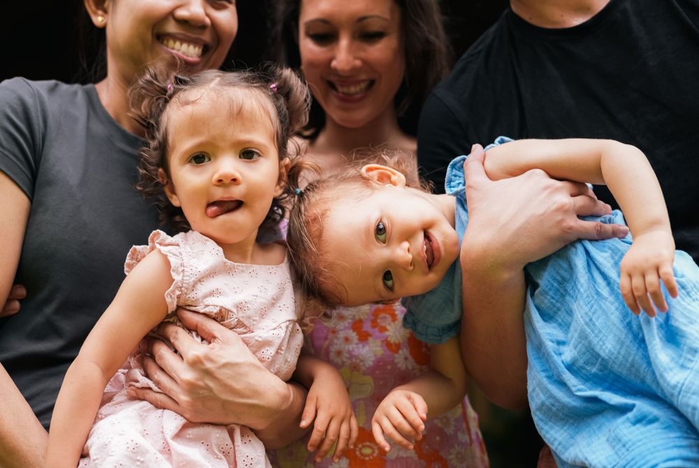 A candid family photo showing playful interaction and laughter in an outdoor setting.