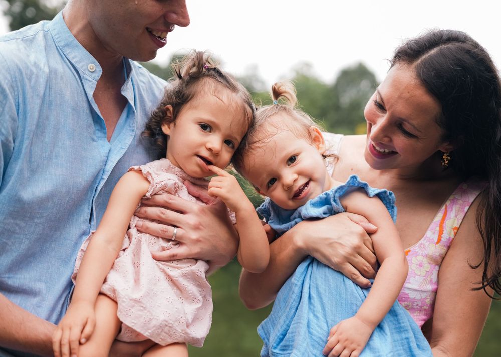 An intimate family moment captured outdoors with natural scenery in the background.