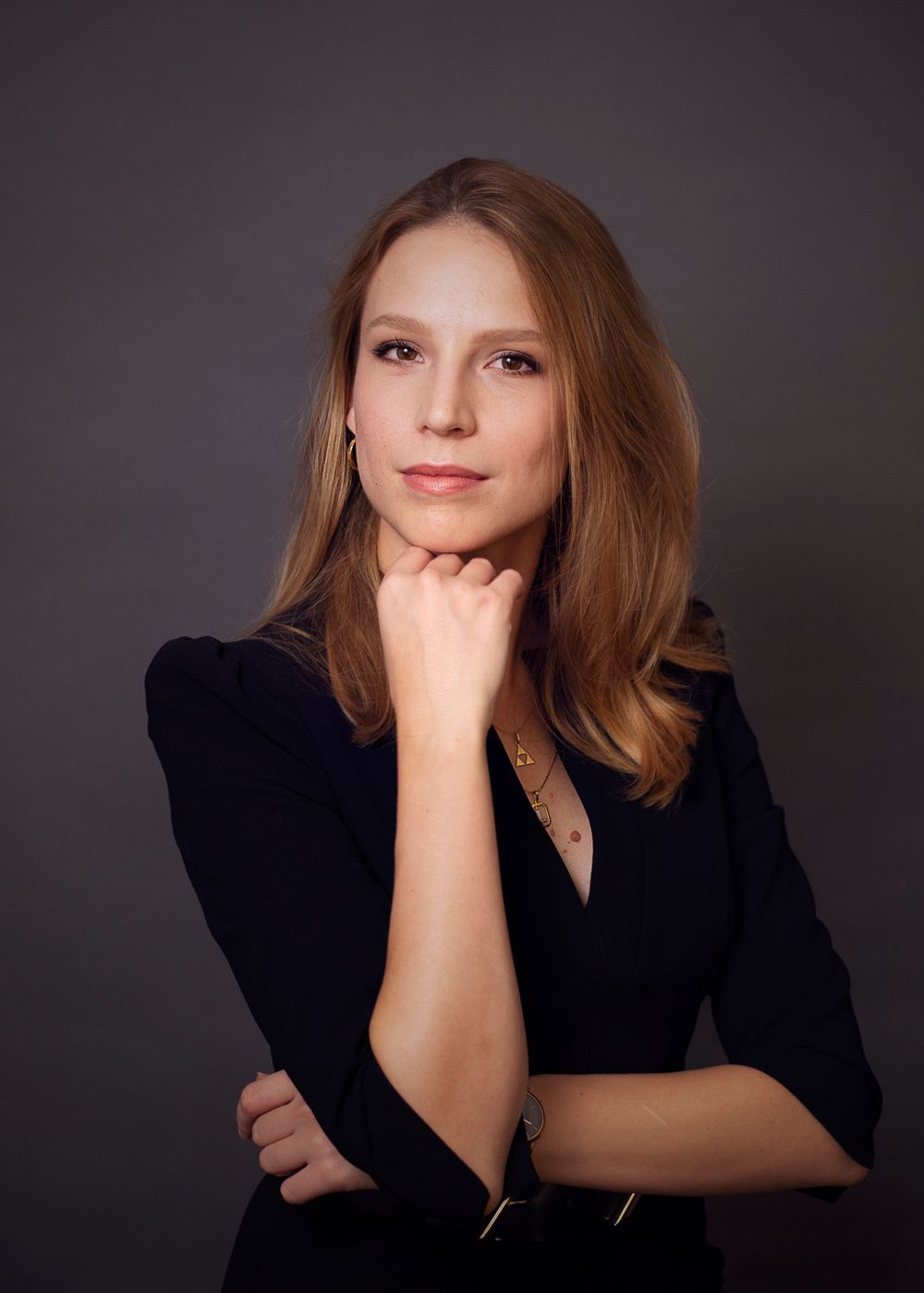 Professional portrait of a person in a black business jacket posing thoughtfully against a dark background.