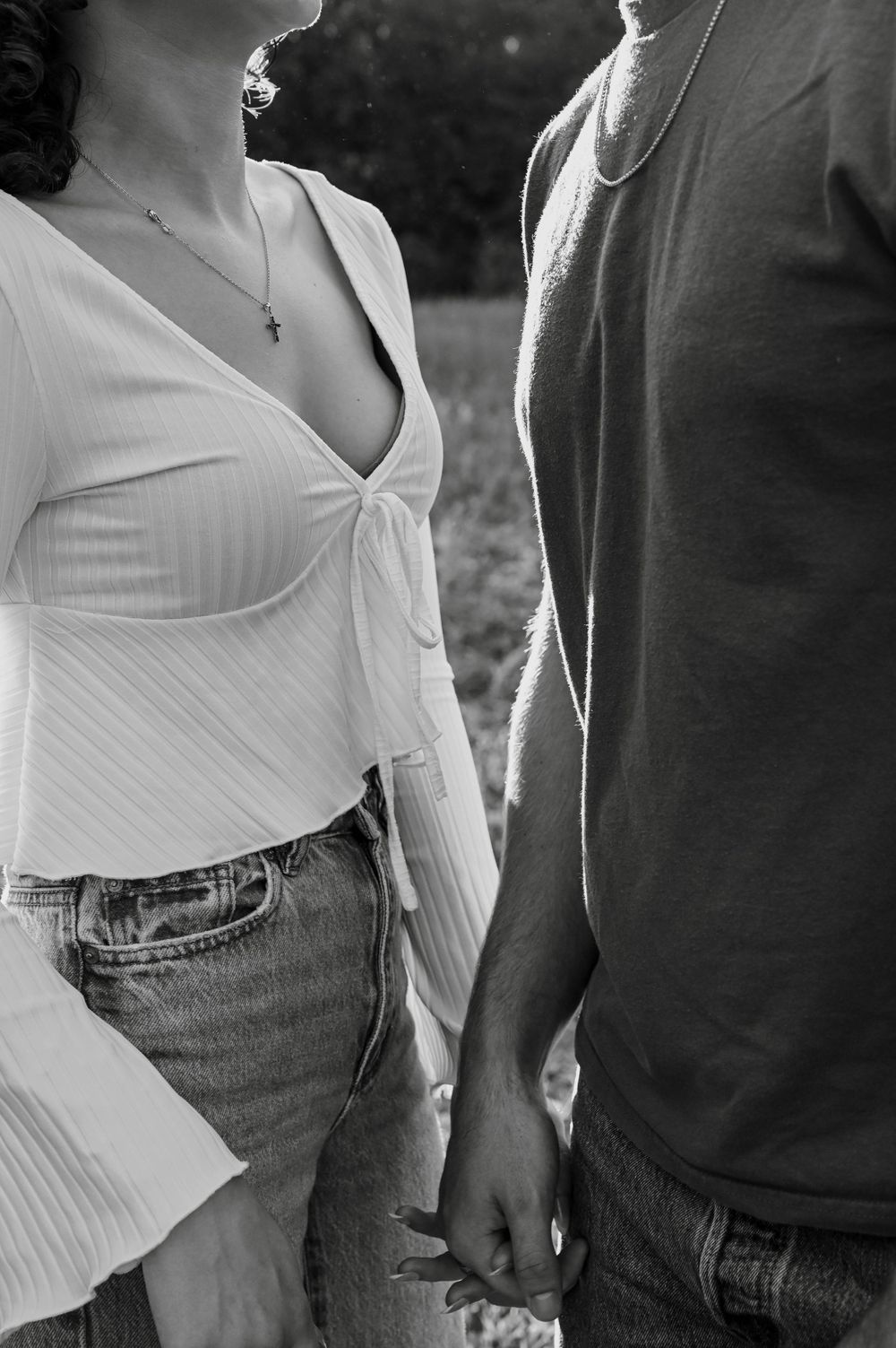 A couple in casual wear holding hands together in a romantic black and white photograph.