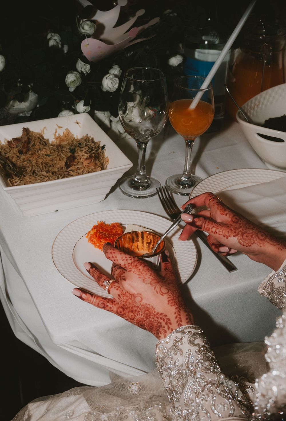 Traditional wedding dinner setting with henna-adorned hands and colorful cuisine.
