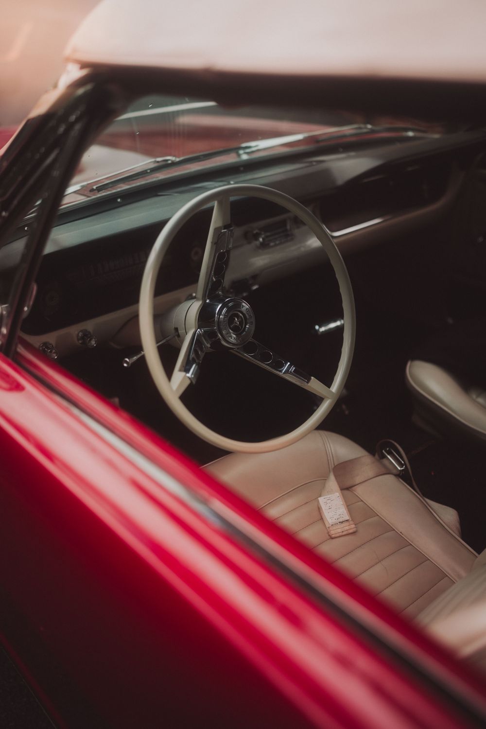 Interior view of a vintage red car showing leather seats and classic steering wheel.