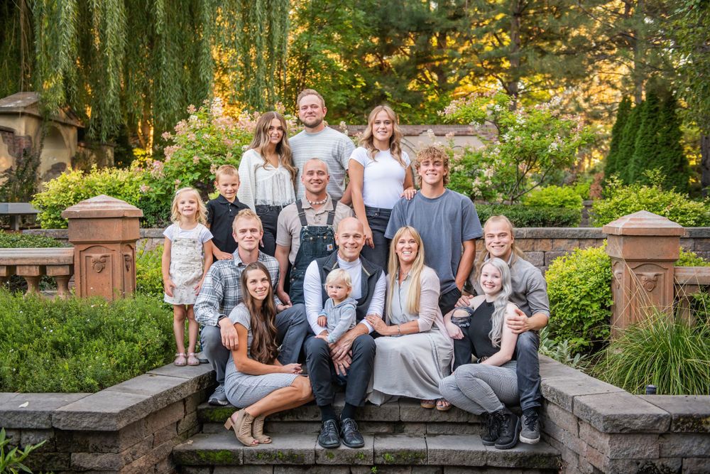 Large group portrait on garden steps surrounded by lush greenery and stone pillars.