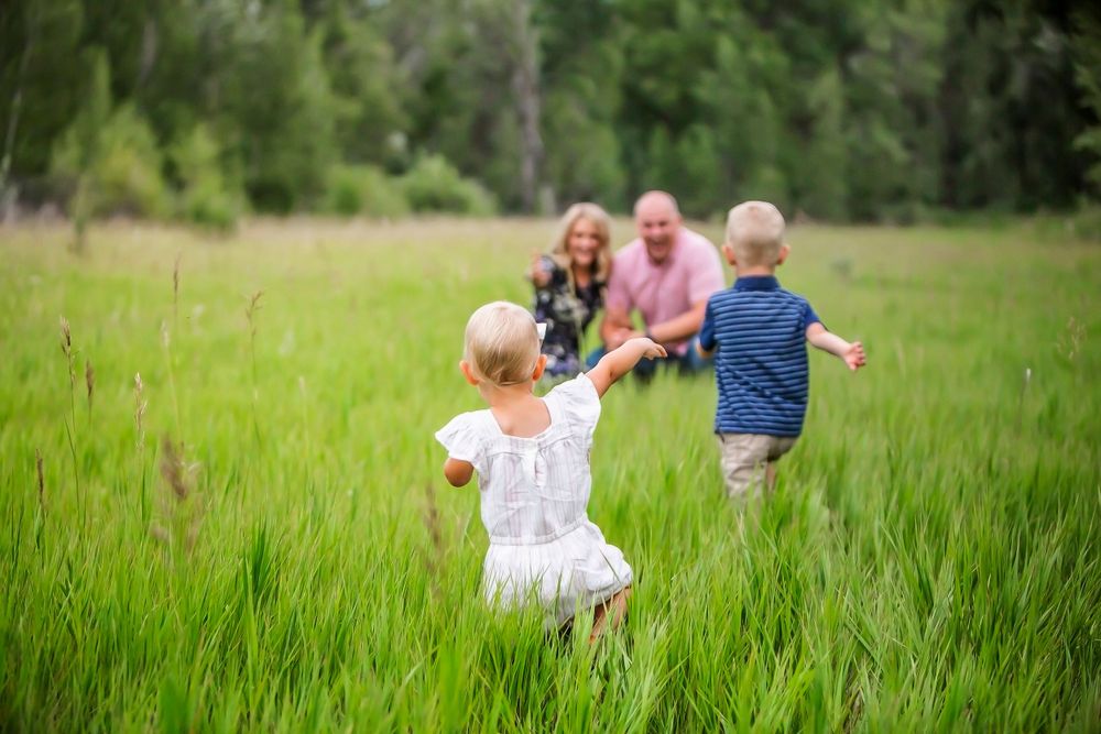 People running through tall grass in a lush green meadow on a sunny summer day.