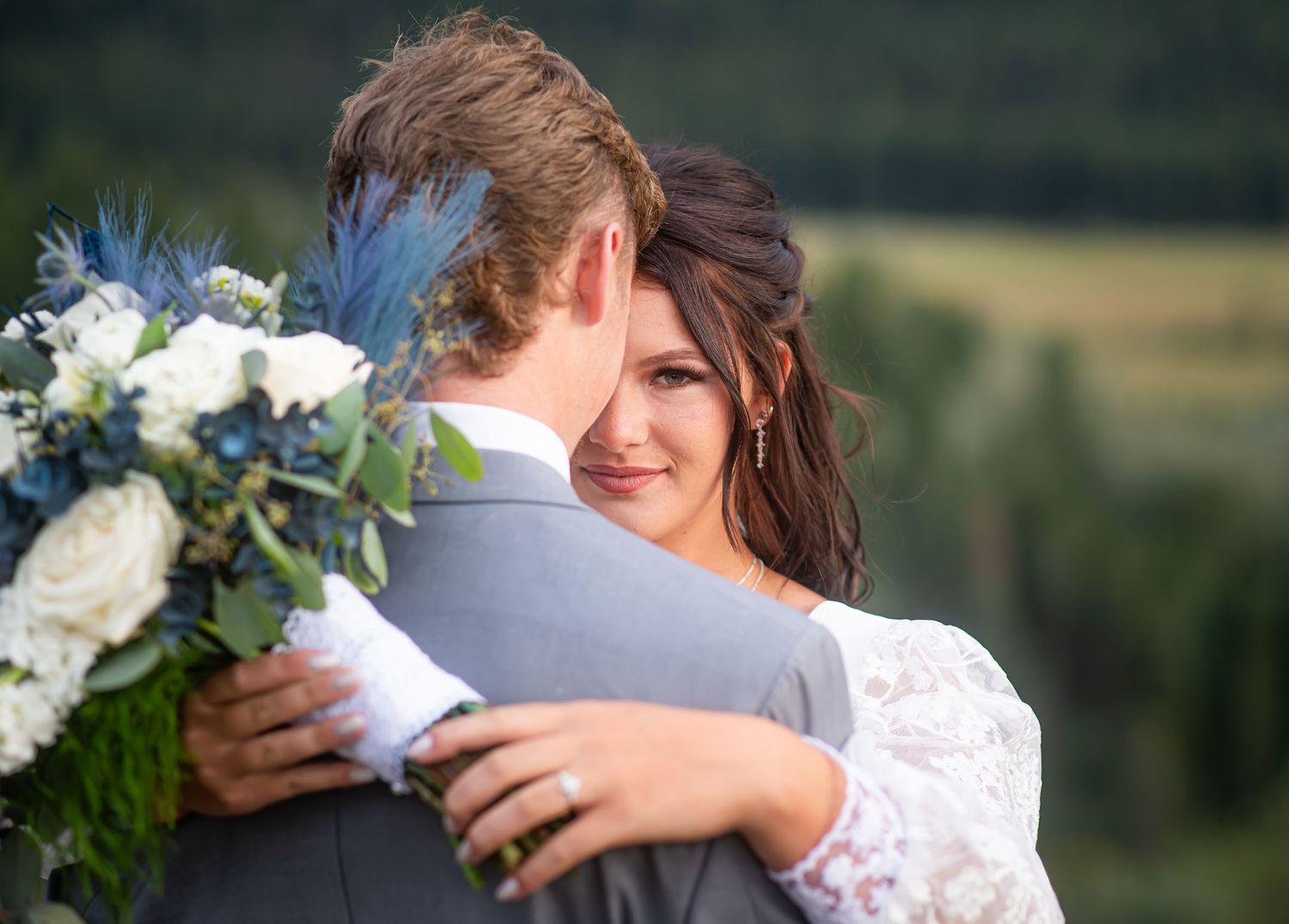 A romantic wedding couple embraces in a desert landscape during a golden sunset with sagebrush and tall grass surrounding them.
