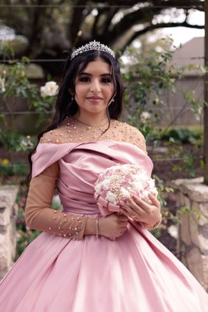 sweet sixteen outdoor portrait of the model in her pink dress holding her bouquet.
