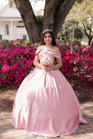 sweet sixteen outdoor portrait of model standing in front of beautiful deep pink flowers