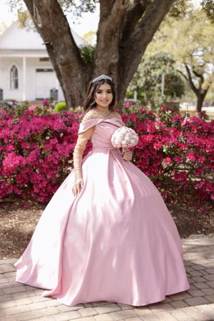 sweet sixteen outdoor portrait of model standing in front of beautiful deep pink flowers