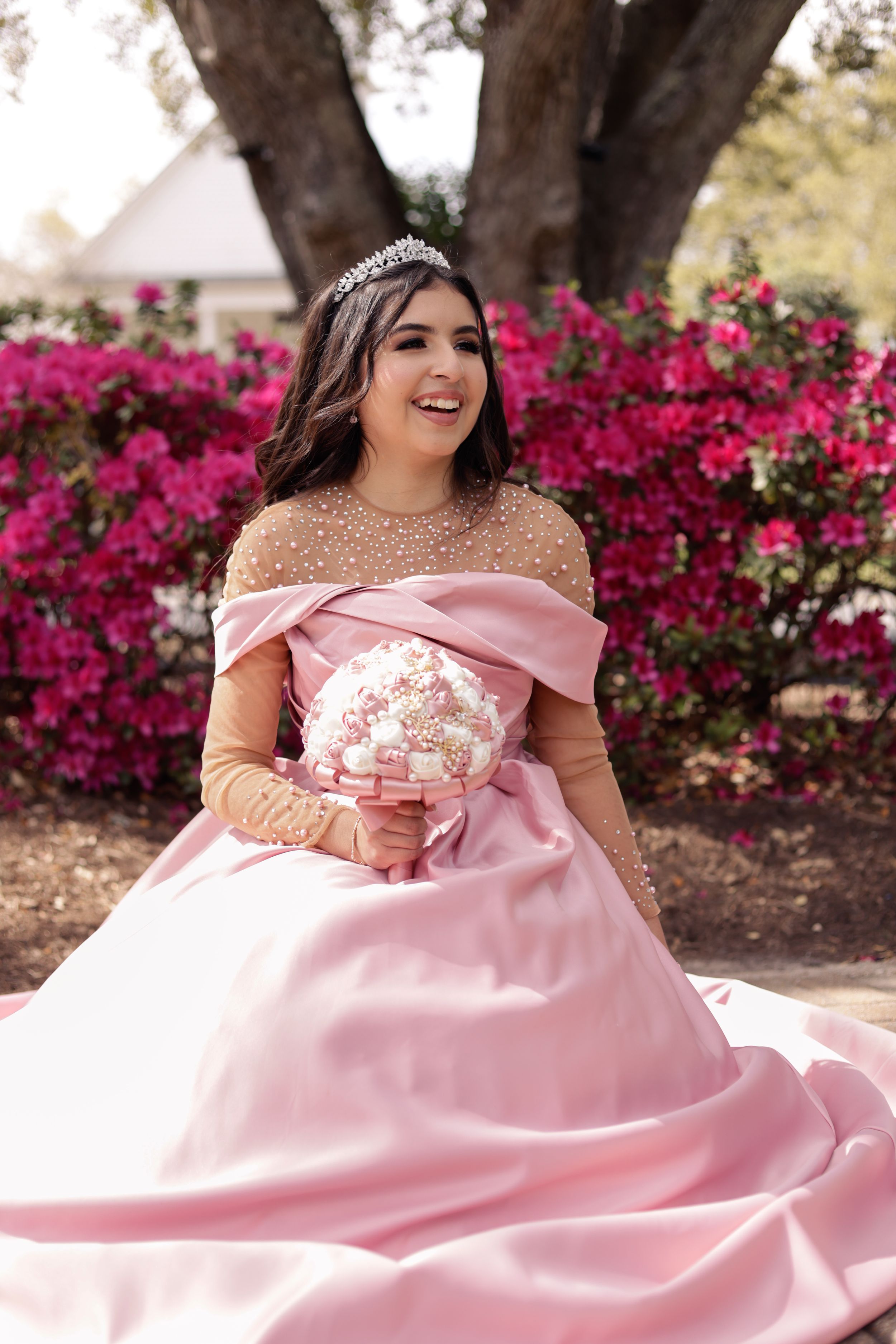 Sweet sixteen outdoor session/portrait of model sitting in front of beautiful deep pink flowers.