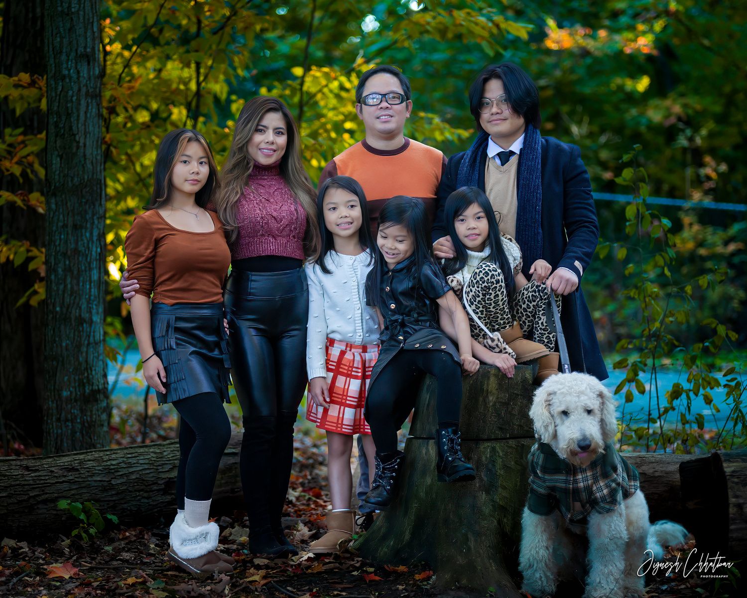 Family of seven with their dog, enjoying a joyful outdoor moment together, surrounded by nature's beauty and vibrant scenery.