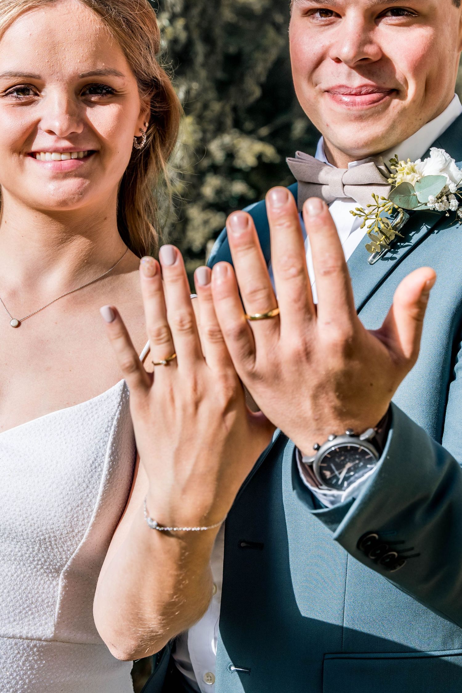 Close-up of newlyweds showing off their wedding rings and jewelry.