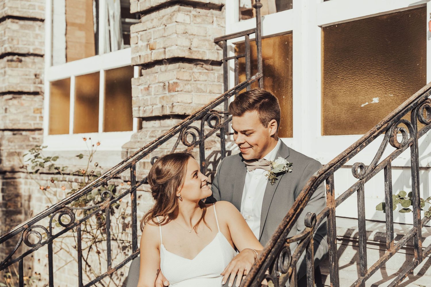 A couple sharing an intimate moment on ornate iron stairs of a historic building.